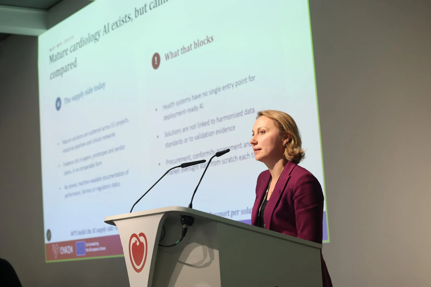 A speaker at the podium presenting a slide on cardiology AI at the CHAIN kick-off meeting